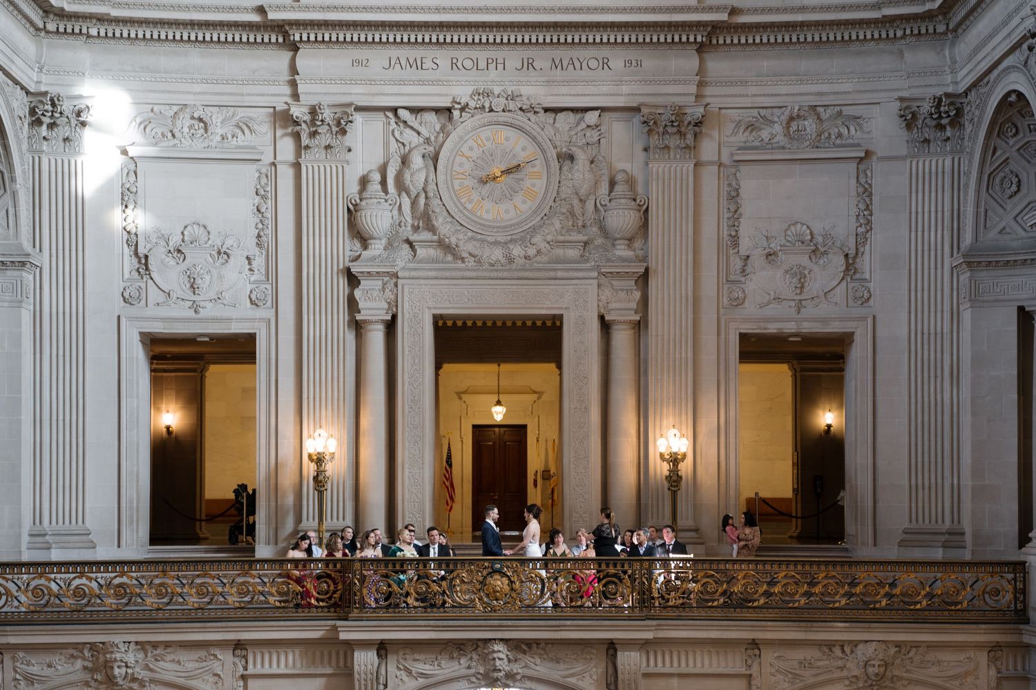 Ornate white marble interior of San Francisco City Hall showcases grand staircase and neoclassical architectural details.