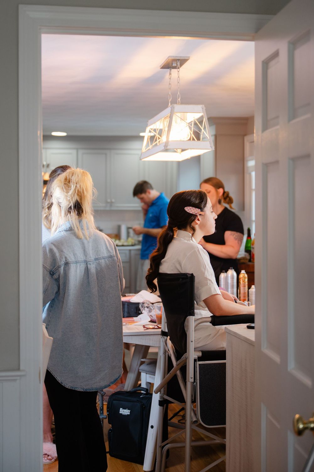 Looking through a door into an area where a bride and her bridesmaids are having their hair and makeup done.