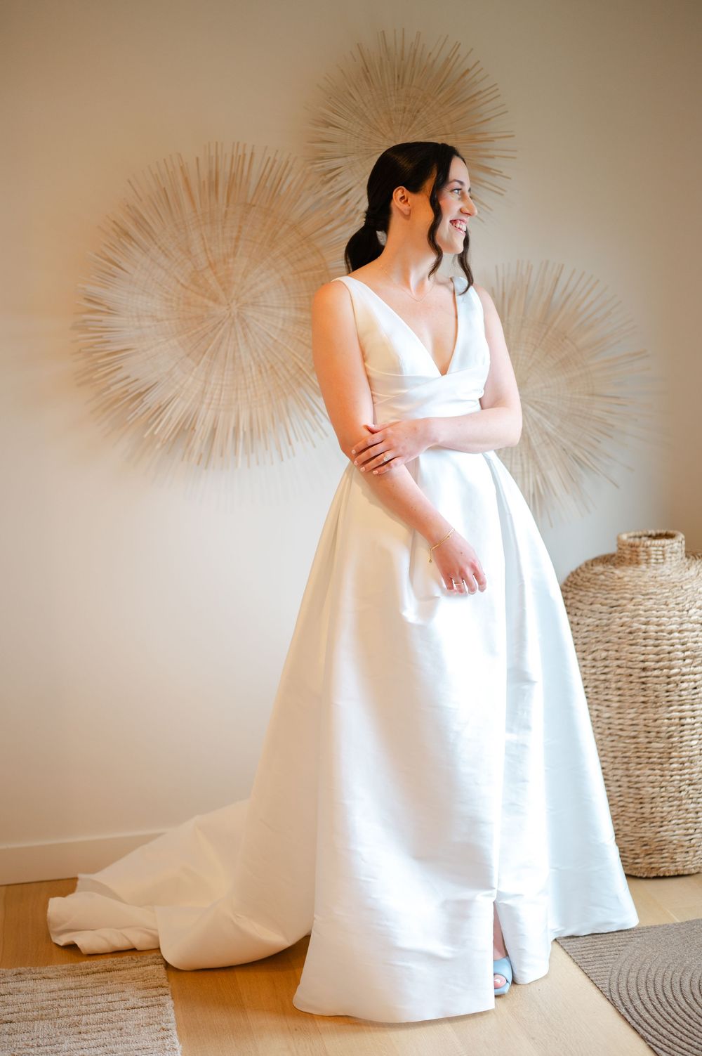 A bride in a flowing white wedding dress poses while showing off the gown's elegant design and texture at the Lakehouse in Halifax, Ma.