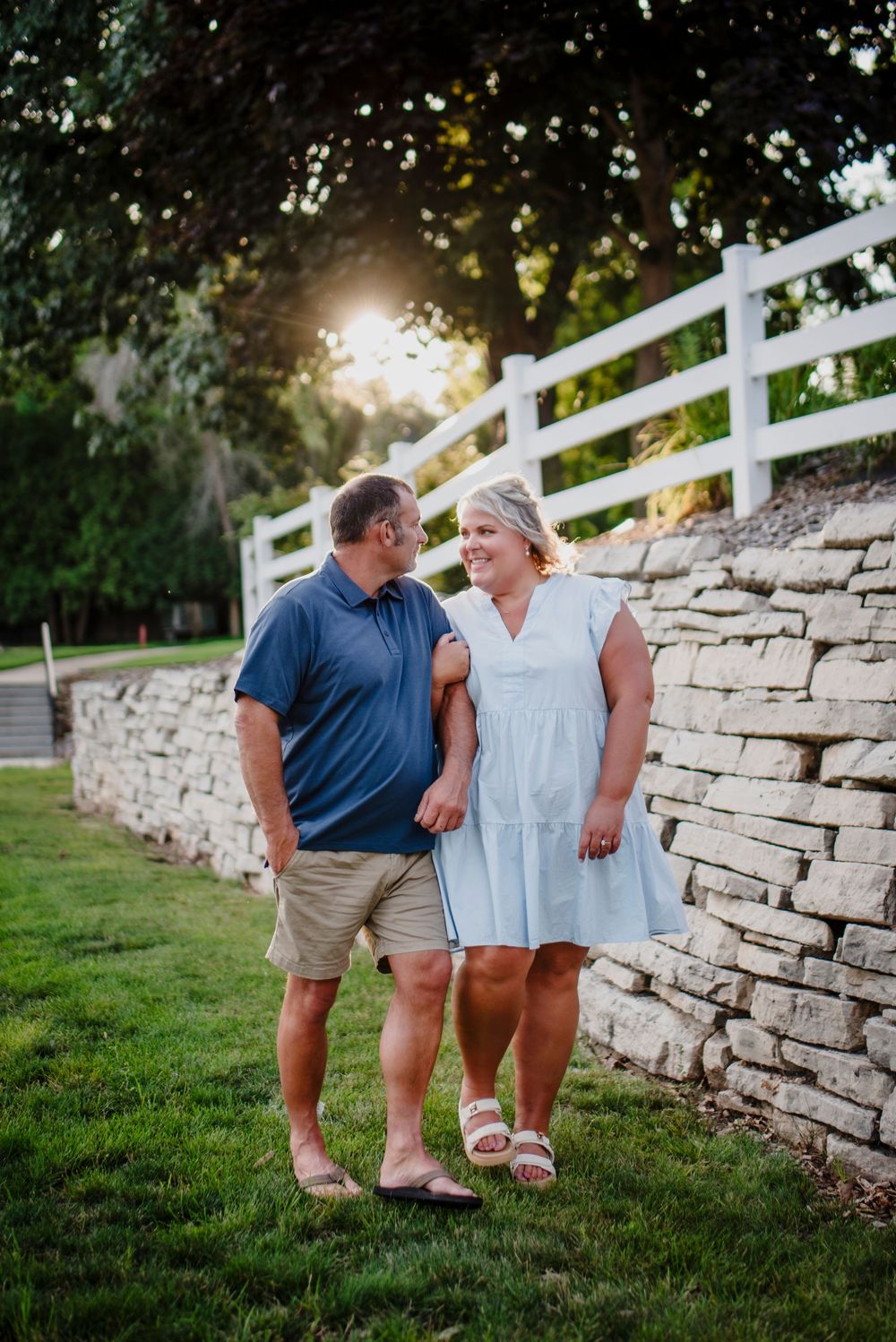 A couple shares a tender moment against a stone wall during golden hour.