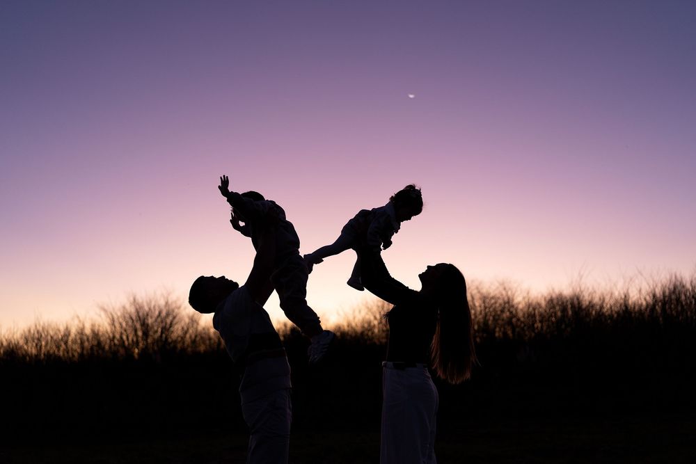 Silhouetted figures dance dramatically against a purple sunset sky along a hilltop horizon.