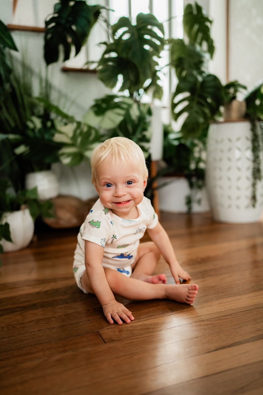 Series of photos showing young child crawling cheerfully across a wood floor with houseplants in background.