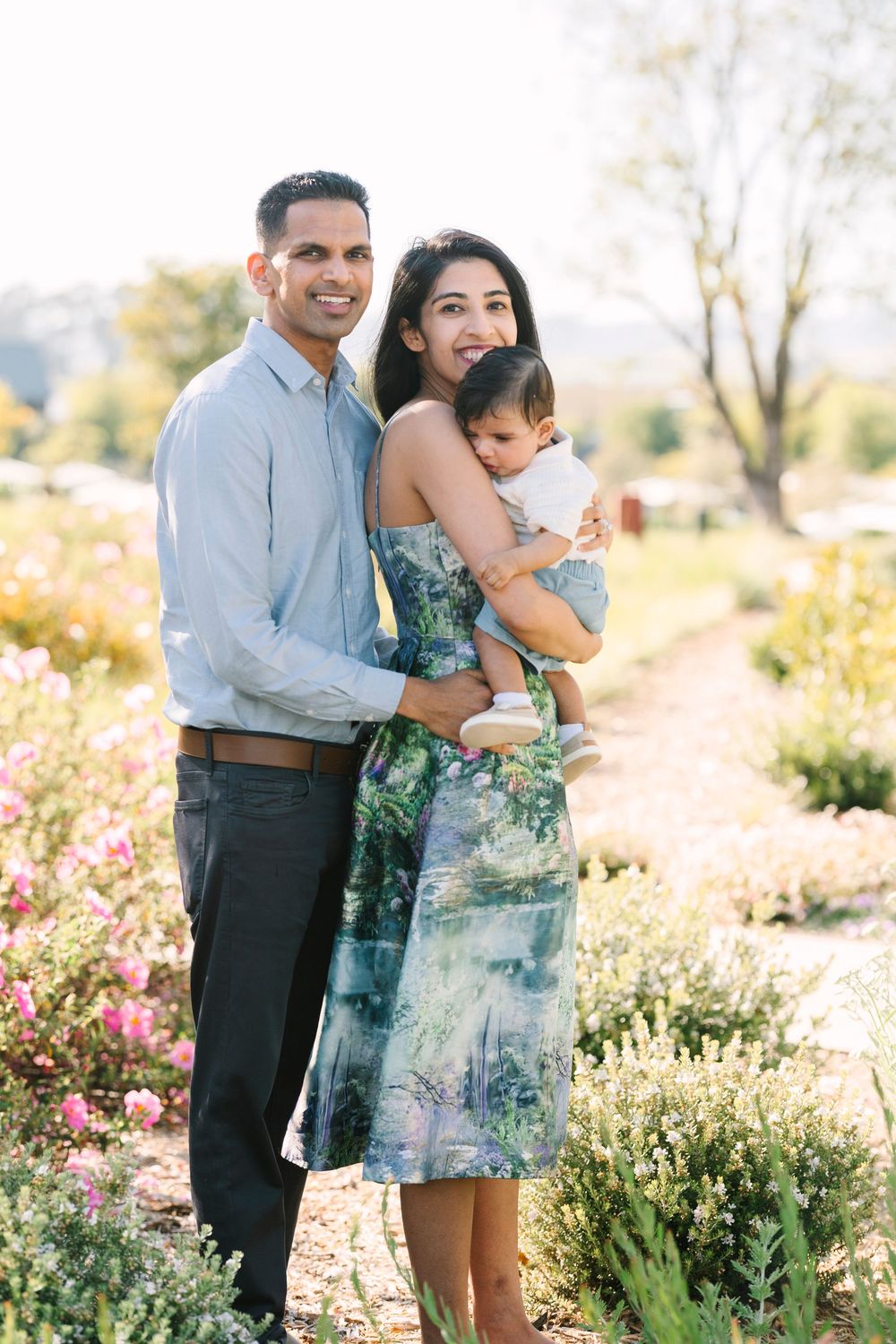 Family portrait session in a blooming garden with floral dresses and coordinated outfits.