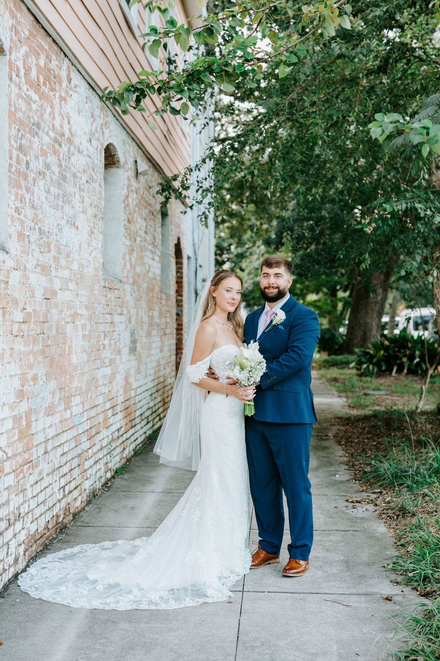A couple shares their first dance moment along a rustic brick wall path surrounded by greenery.