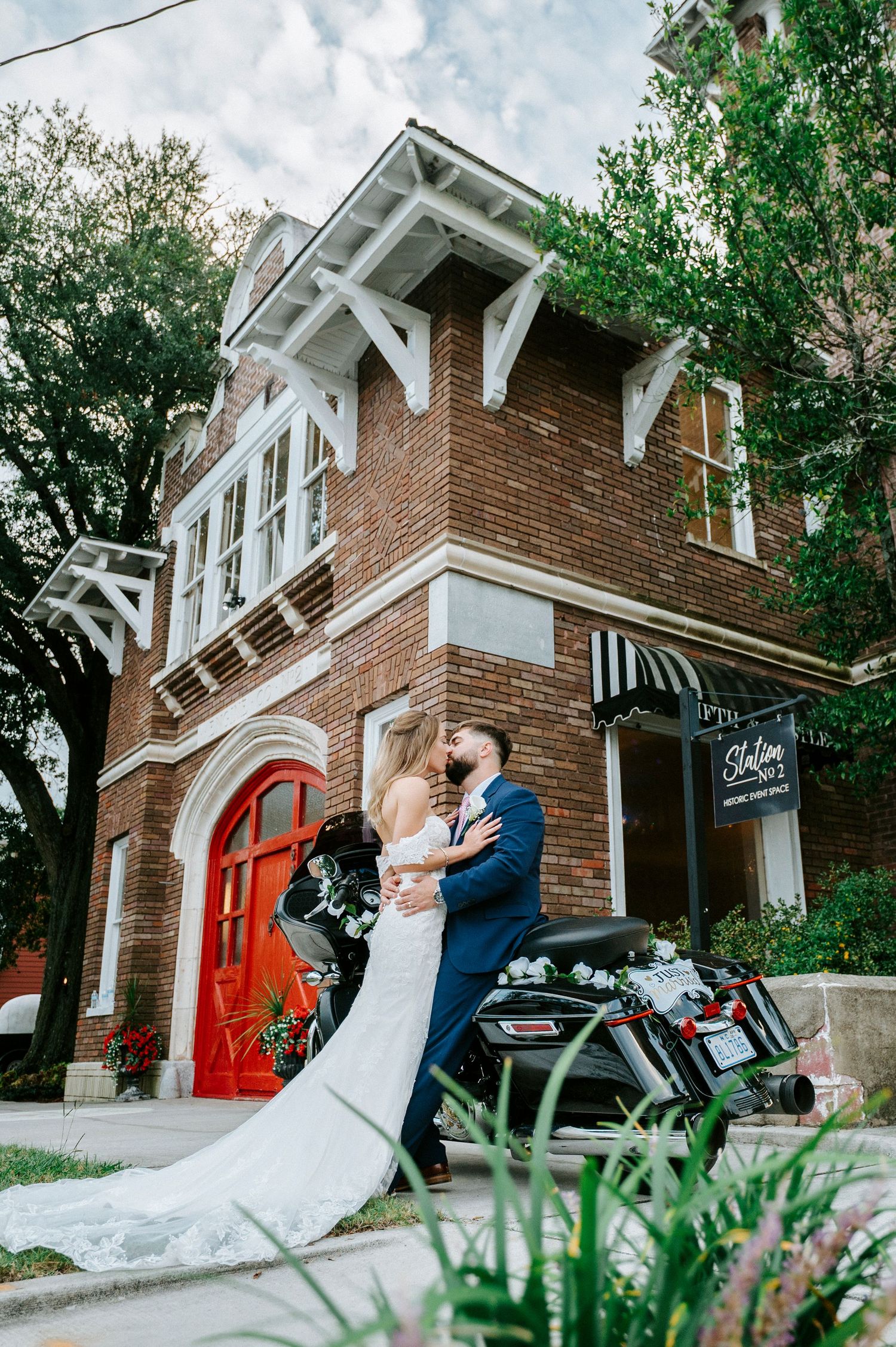 Wedding couple shares romantic moments outside a brick church with a red door.