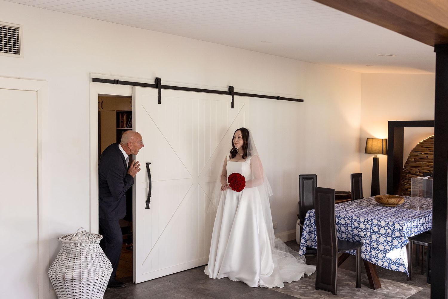 Dad pops his head around a corning to see his daughter ready in her wedding dress for the first time.