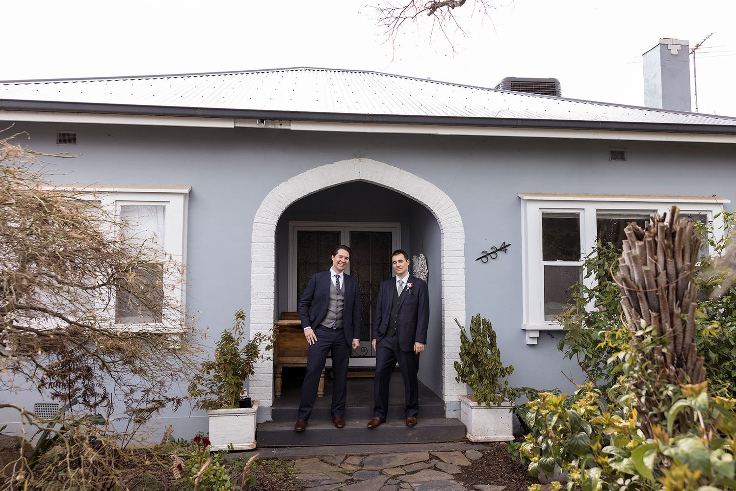Groom and Best Man stand together in the Archway entrance of an old Albury House during wedding Preparations.
