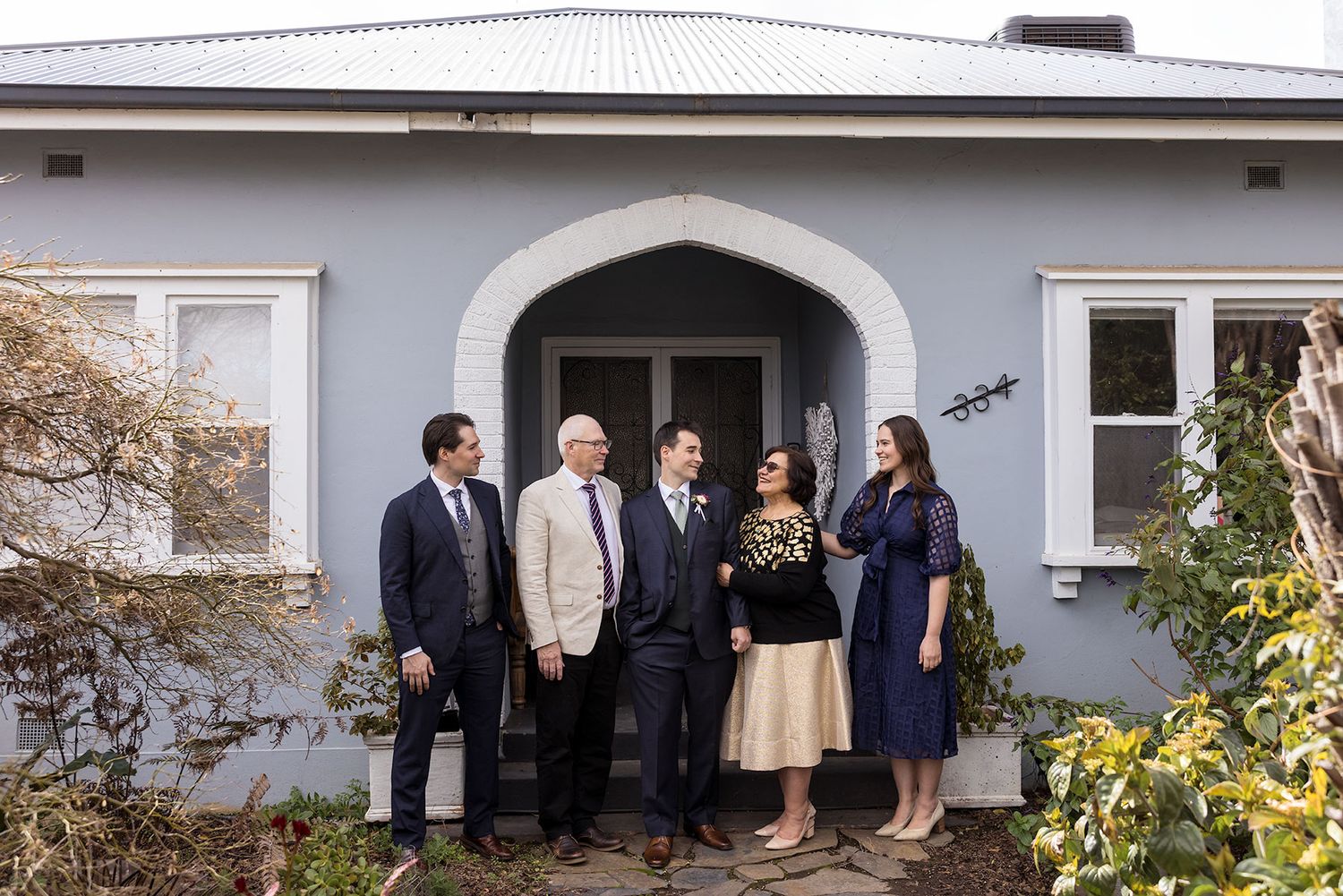 Groom and his family stand together in the Archway entrance of an old Albury House during wedding Preparations.