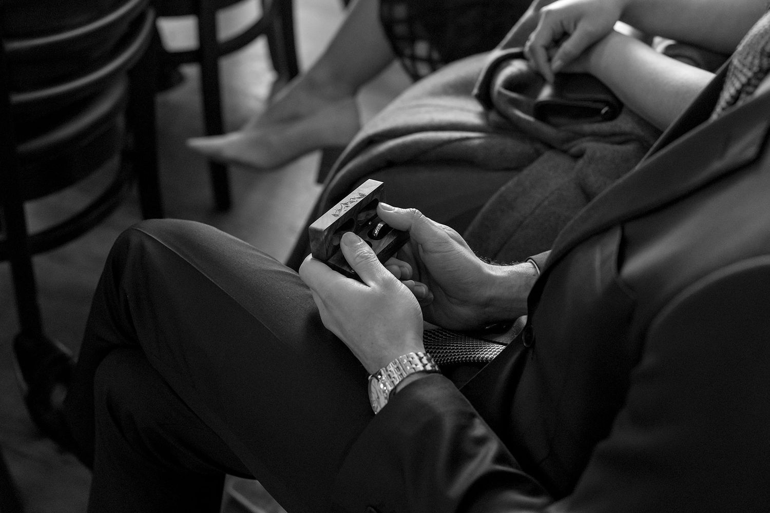 Black and white image shows a wedding guest holding a wooden box with the wedding rings in it.