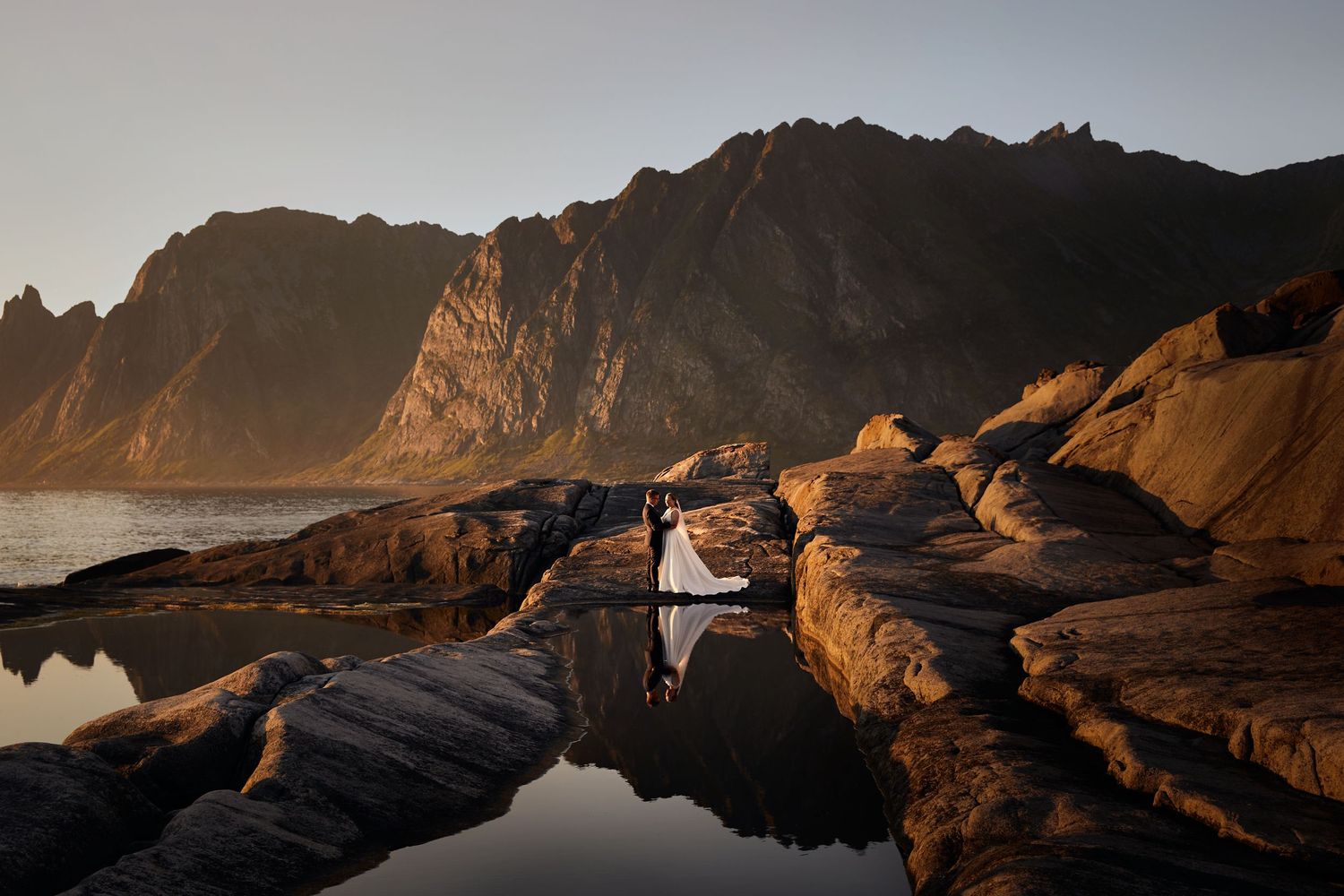 Bride and groom in Senja with golden midnight sun and the Okshornan mountains (The Devils jaw)  in the background