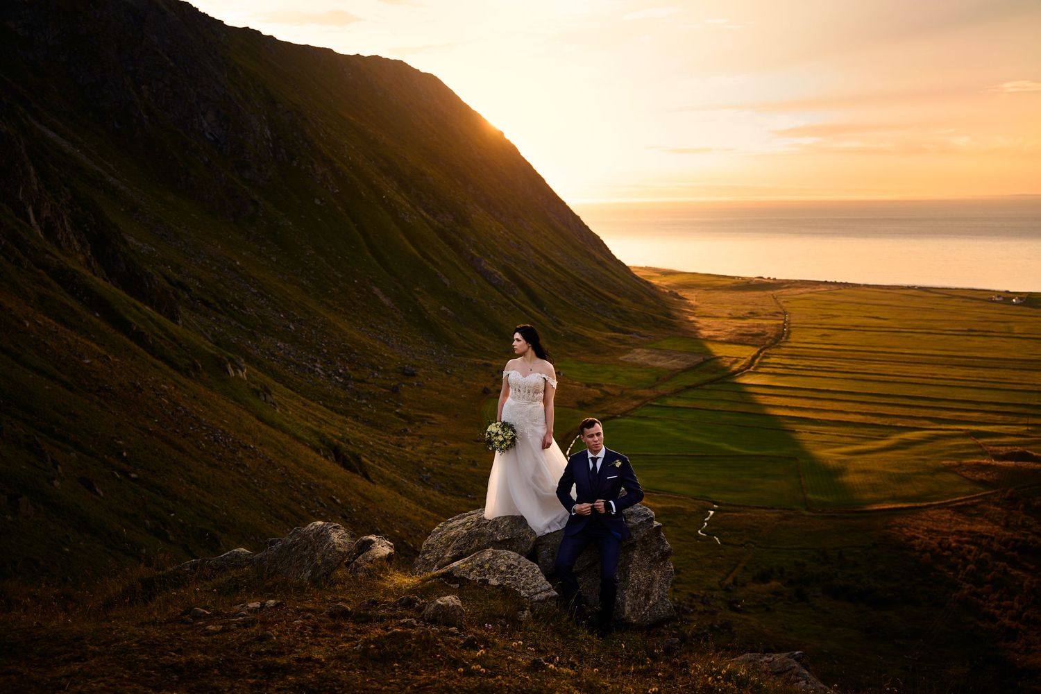 Bride and groom posing amongst the Lofoten mountains in golden midnight sun