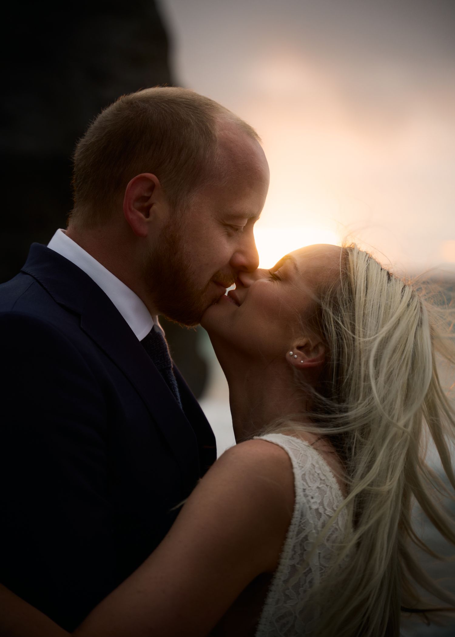 Bride and groom kissing backlit from the golden sun just above the horizon at the Uttakleiv beach, Lofoten