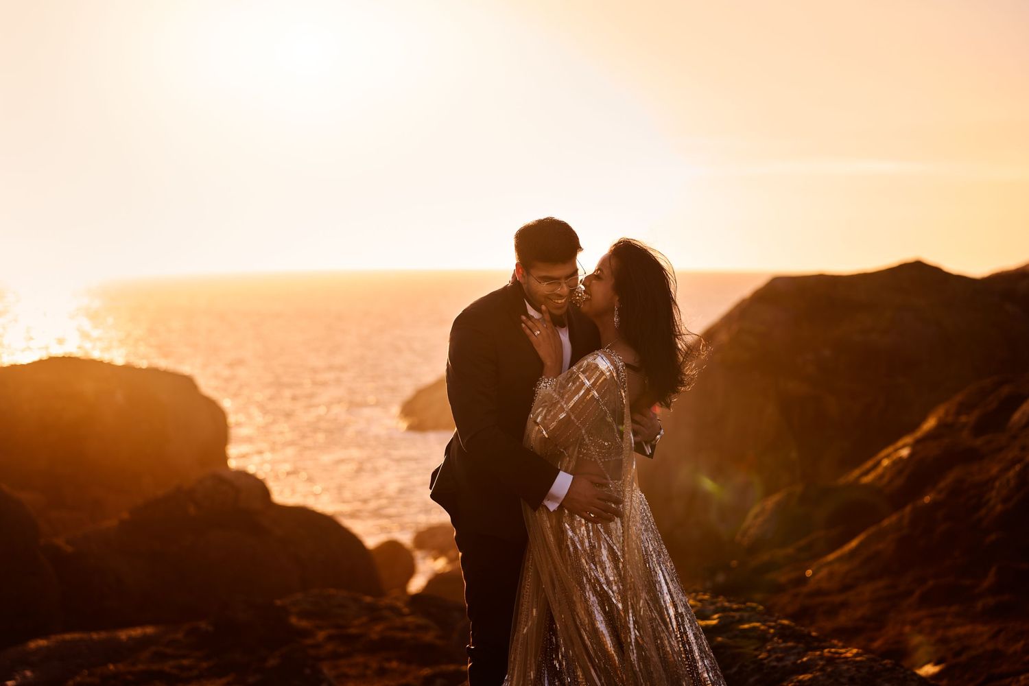 Bride and groom embracing each other in golden midnight sun