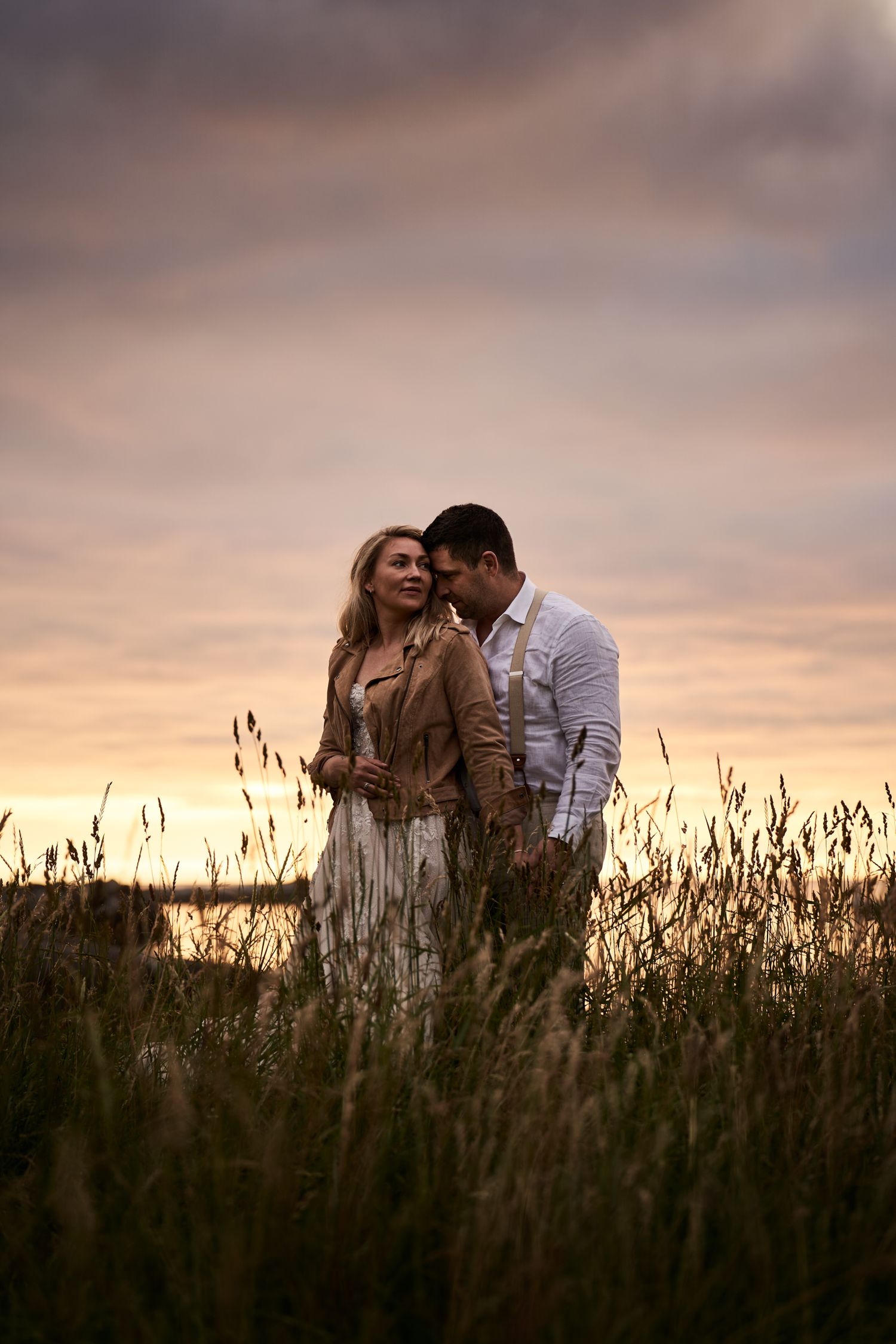 Bride and groom embracing each other on the beach in midnight sun