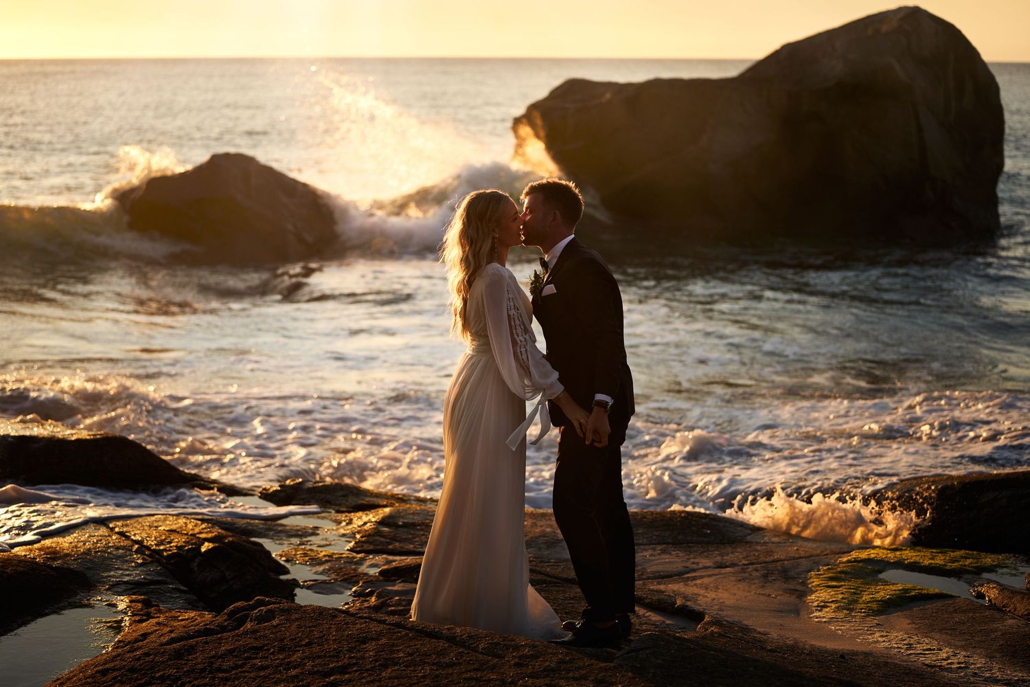 Bride and groom kissing on the beach in the golden midnight sun, Lofoten