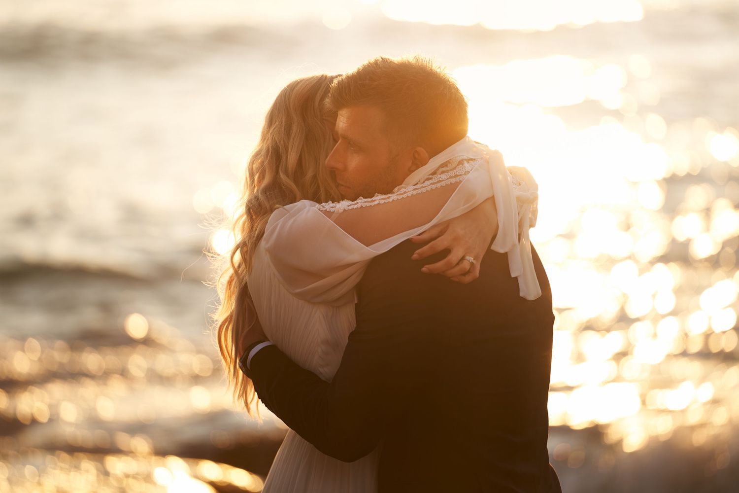 Bride and groom hugging backlit from the golden midnight sun at Uttakleiv beach, Lofoten