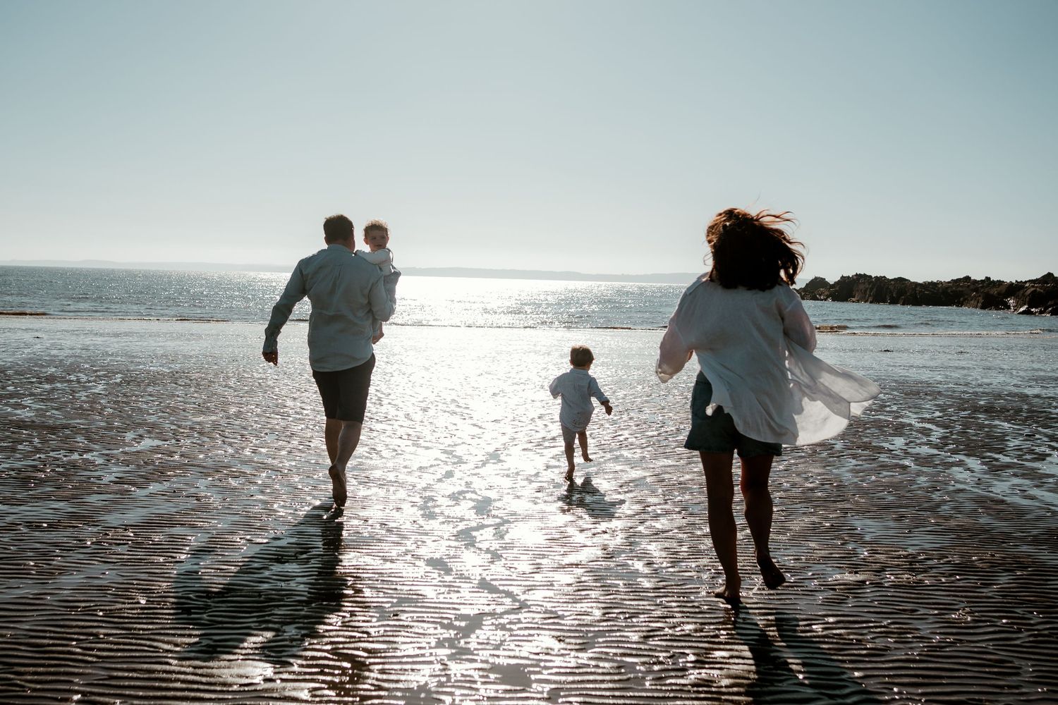 Family running on beach during outdoor photoshoot in Dumfries & Galloway