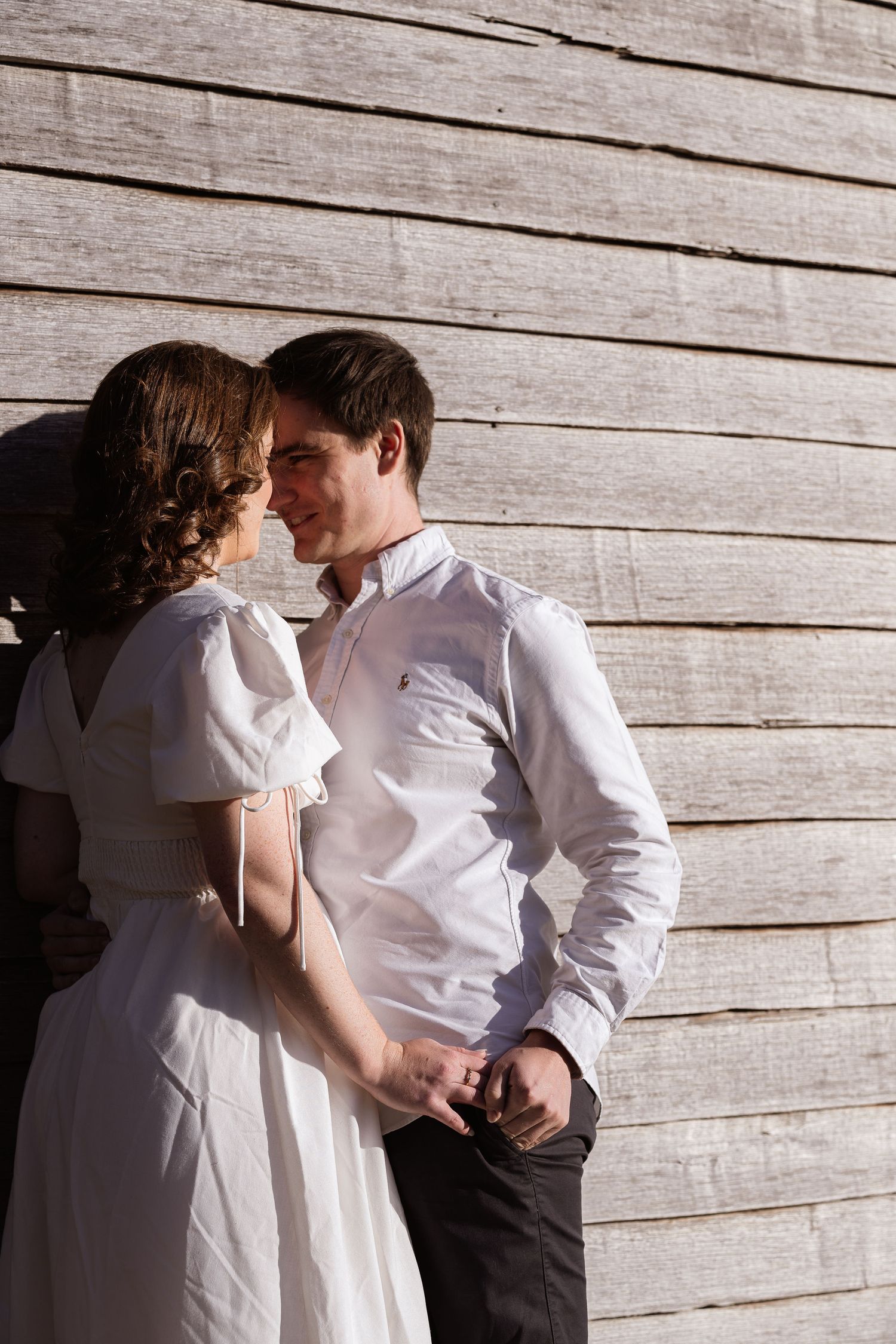 A romantic sequence of photos showing a couple in white shirts against a rustic wooden wall background.