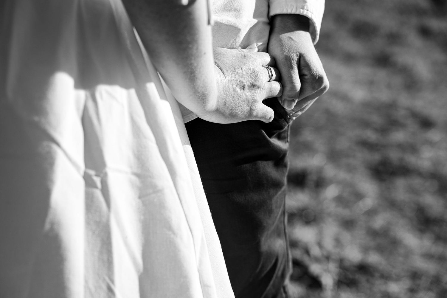 Two people in elegant wedding attire embrace while dancing during a black and white reception moment.
