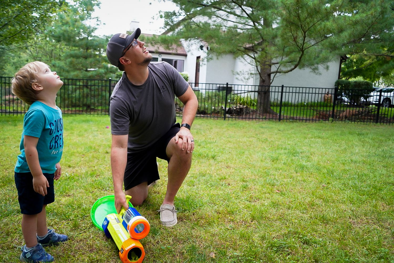 Person playing a balloon popping game with a squirt gun during an outdoor summer party on a grassy lawn.