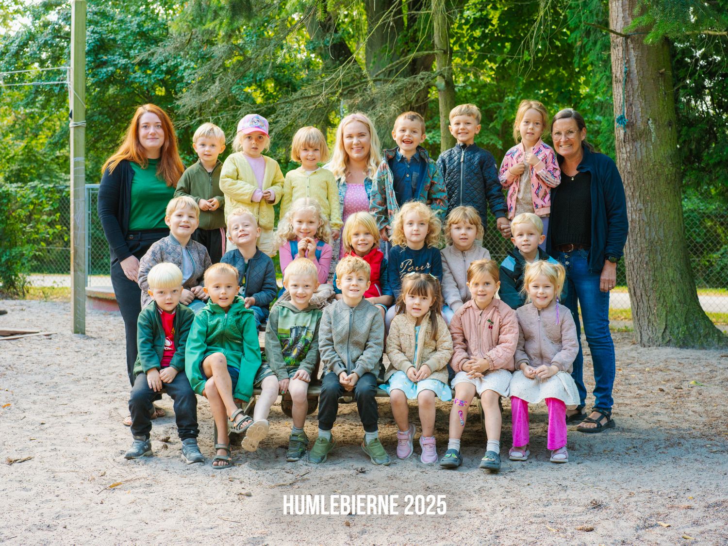 Children sitting on wooden logs outdoors during a photo session at a park.