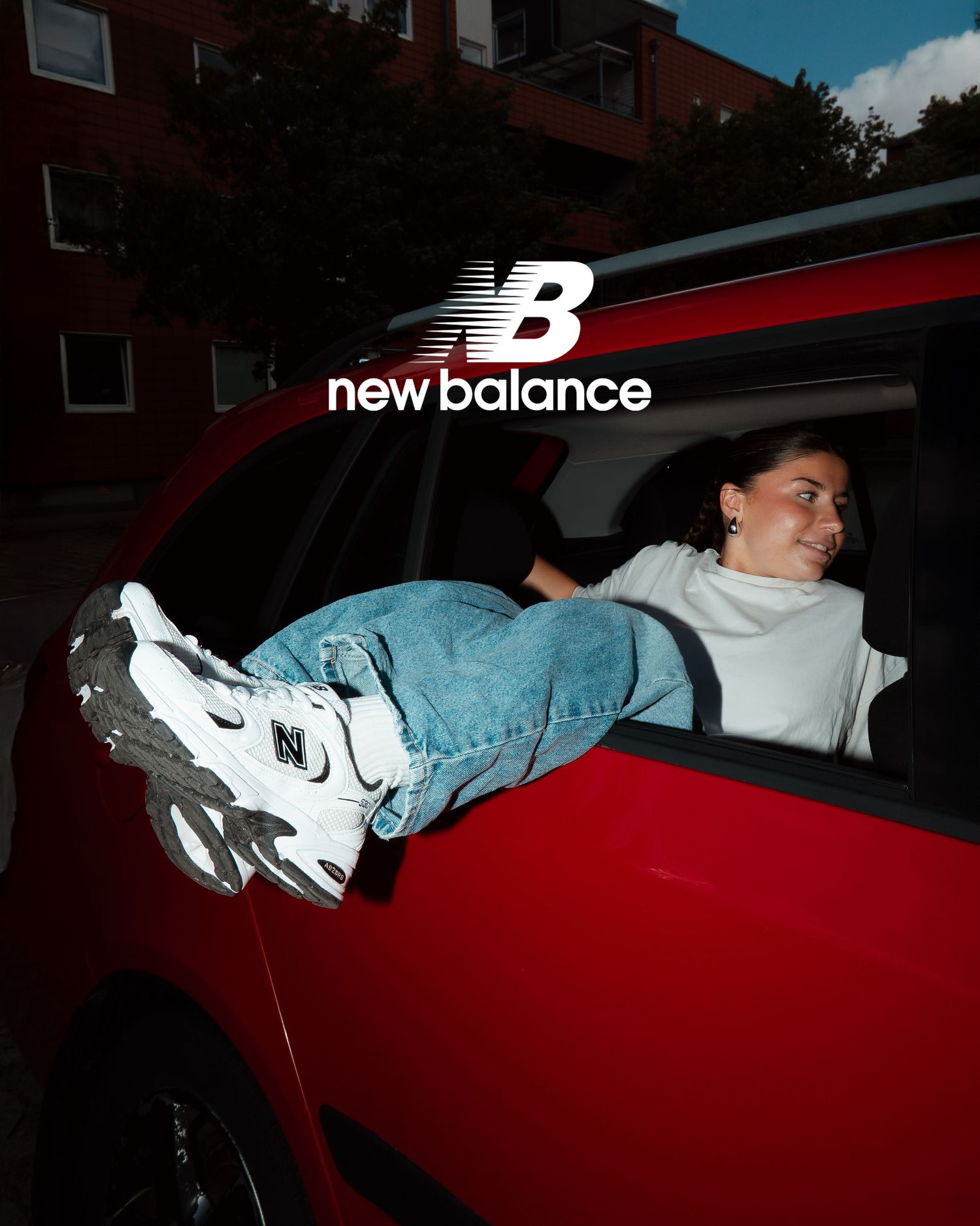 New Balance advertisement featuring a red car against dark moody lighting.