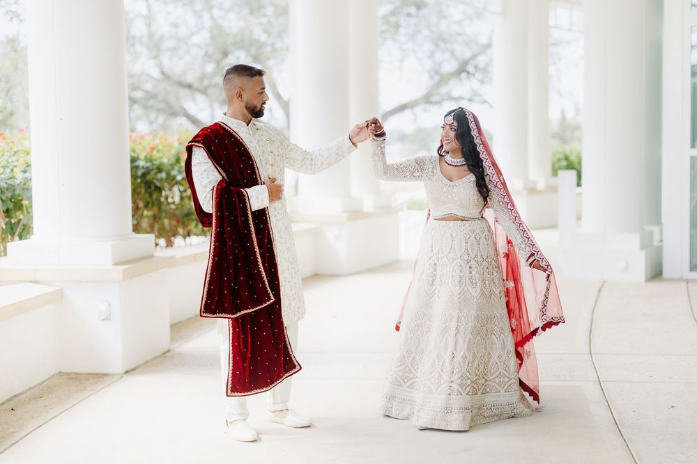A couple in traditional Albanian wedding attire walks along a white covered veranda during their wedding ceremony.