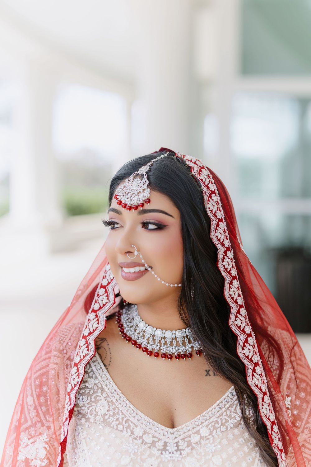 Beautiful bridal portrait in traditional South Asian wedding attire with red dupatta and intricate silver jewelry.