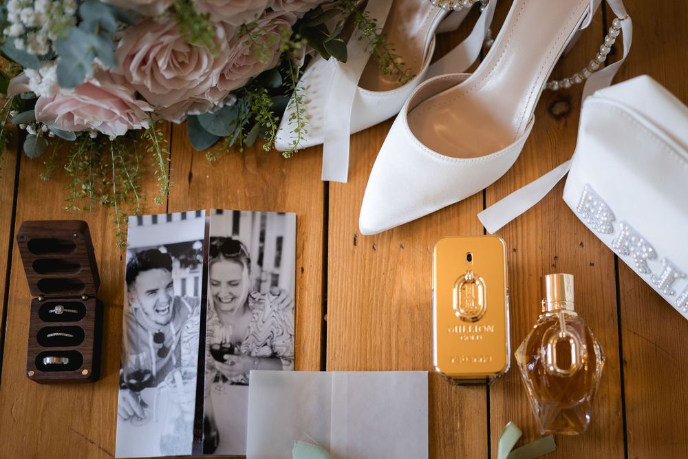 Wedding day details and photographs arranged artistically on a wooden surface.