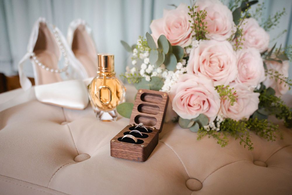 Pink roses and delicate floral arrangements on white wedding reception table.