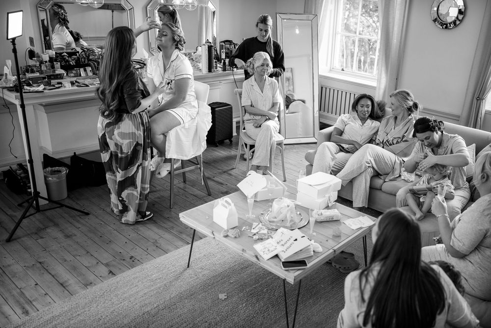 Wedding preparation scene with multiple people gathered in a bright indoor setting.
