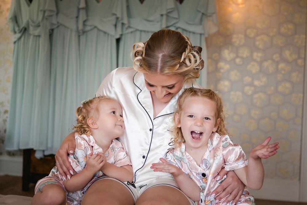 Bridesmaids in pink robes sharing laughter during wedding preparations.