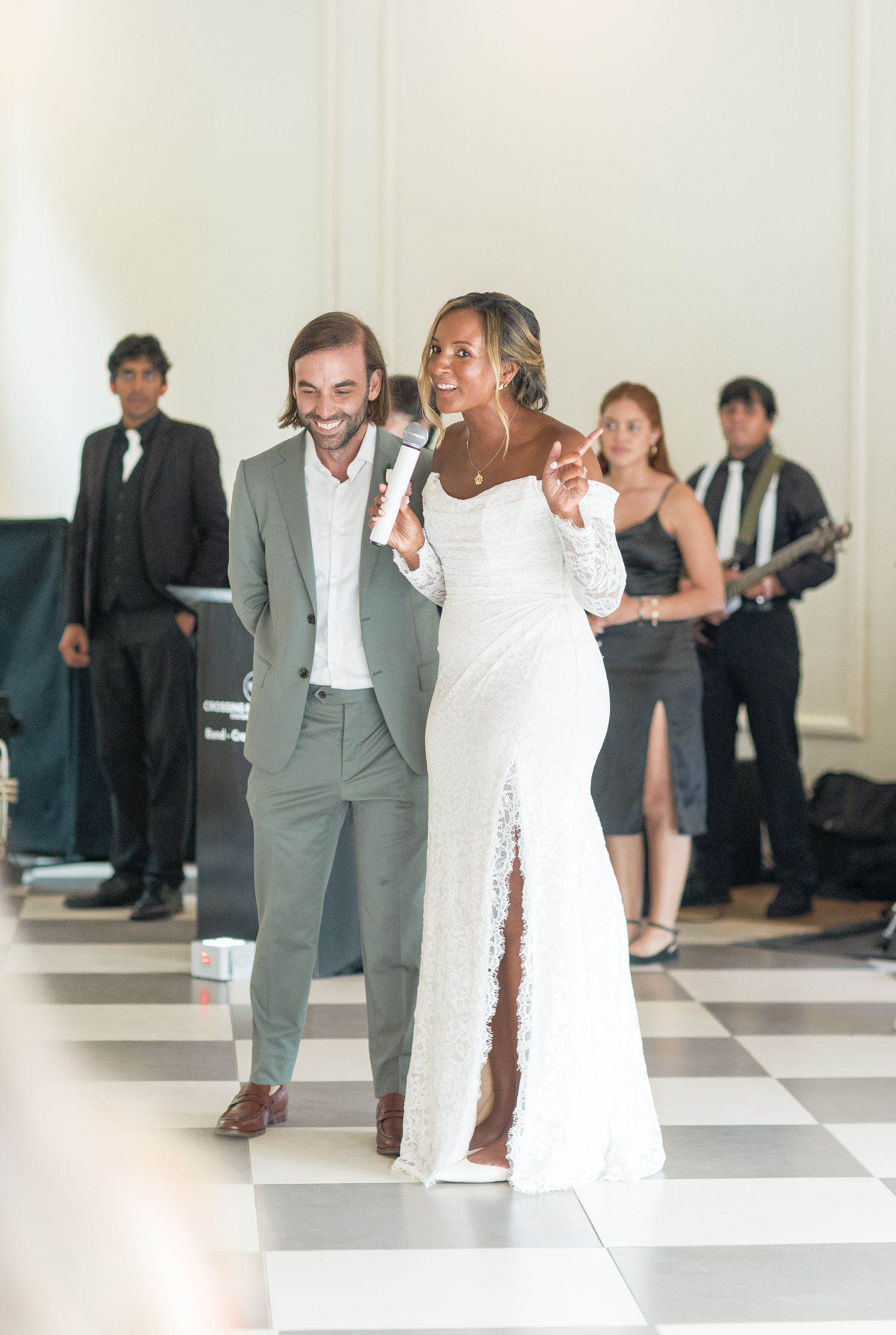 A couple dances together at a formal event, with the woman wearing a white dress and man in gray suit.