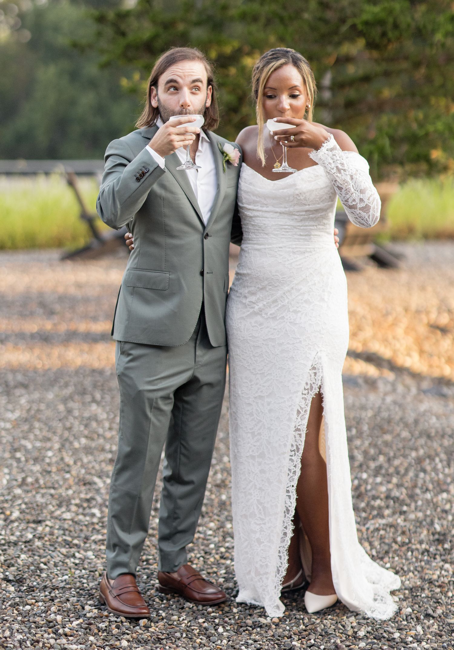 A couple in wedding attire shares a playful moment while taking outdoor photos at their countryside wedding ceremony.
