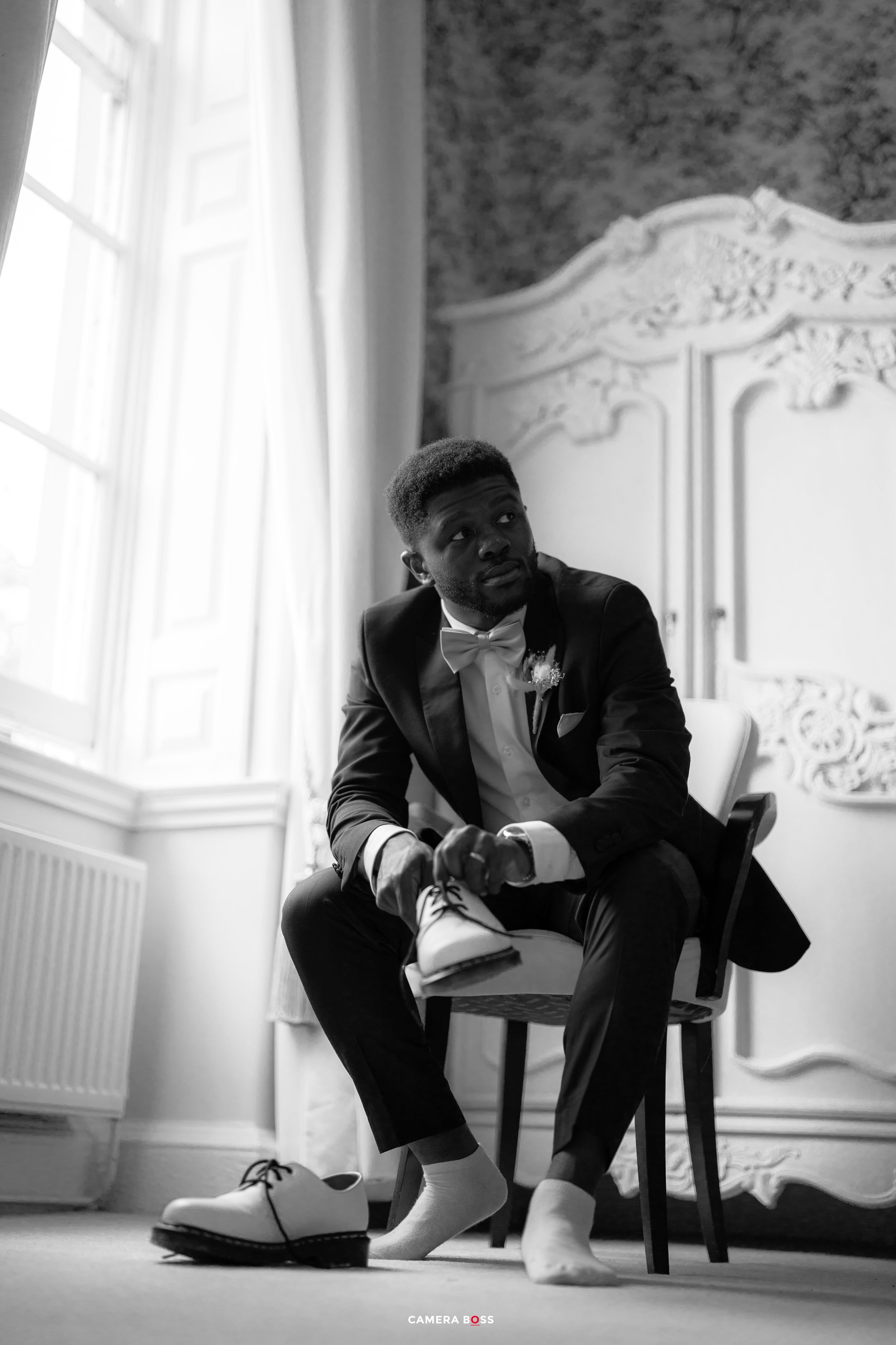 Black and white sequence of person reading book while seated in elegant room with ornate moldings and large windows.