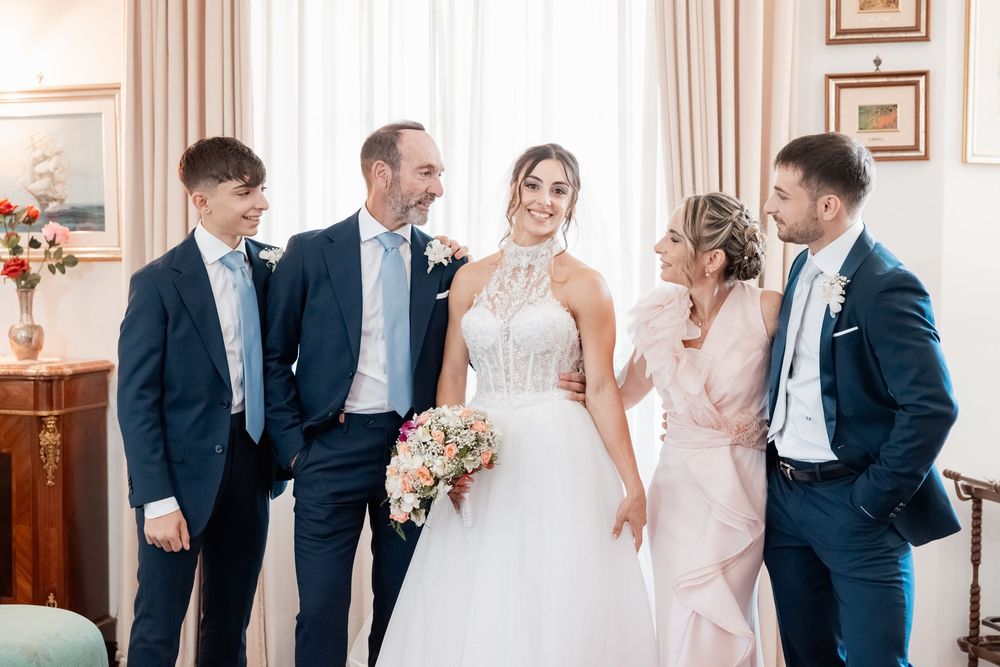Wedding party sharing joyful laughter and candid moments in an elegant room with cream curtains and ornate decor.