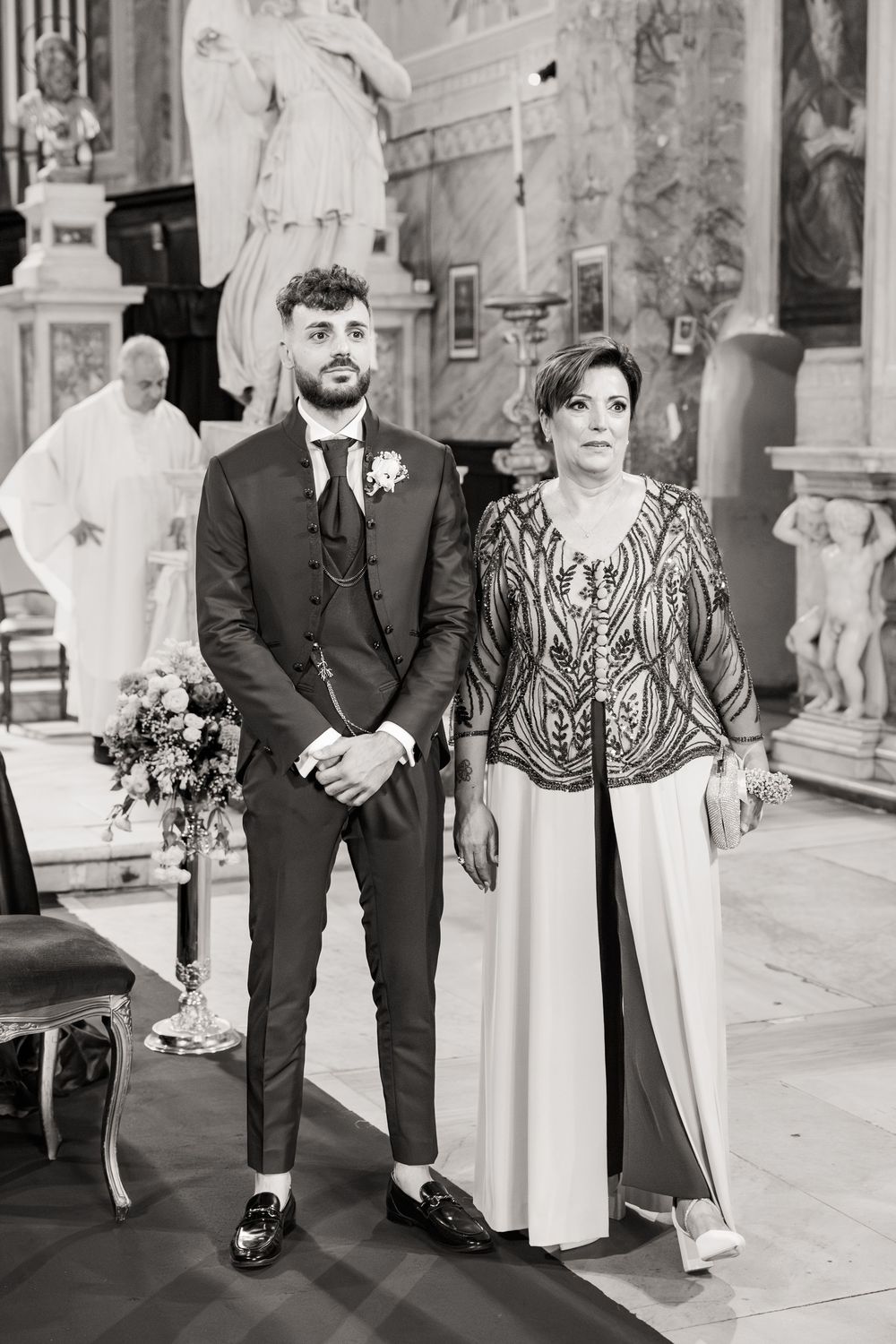 Black and white wedding photos showing small group walking while arm in arm through a classic architectural setting.