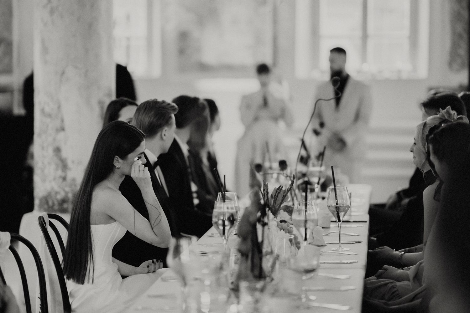 Guests gather in a bright room with ornate architectural details for a formal celebration.