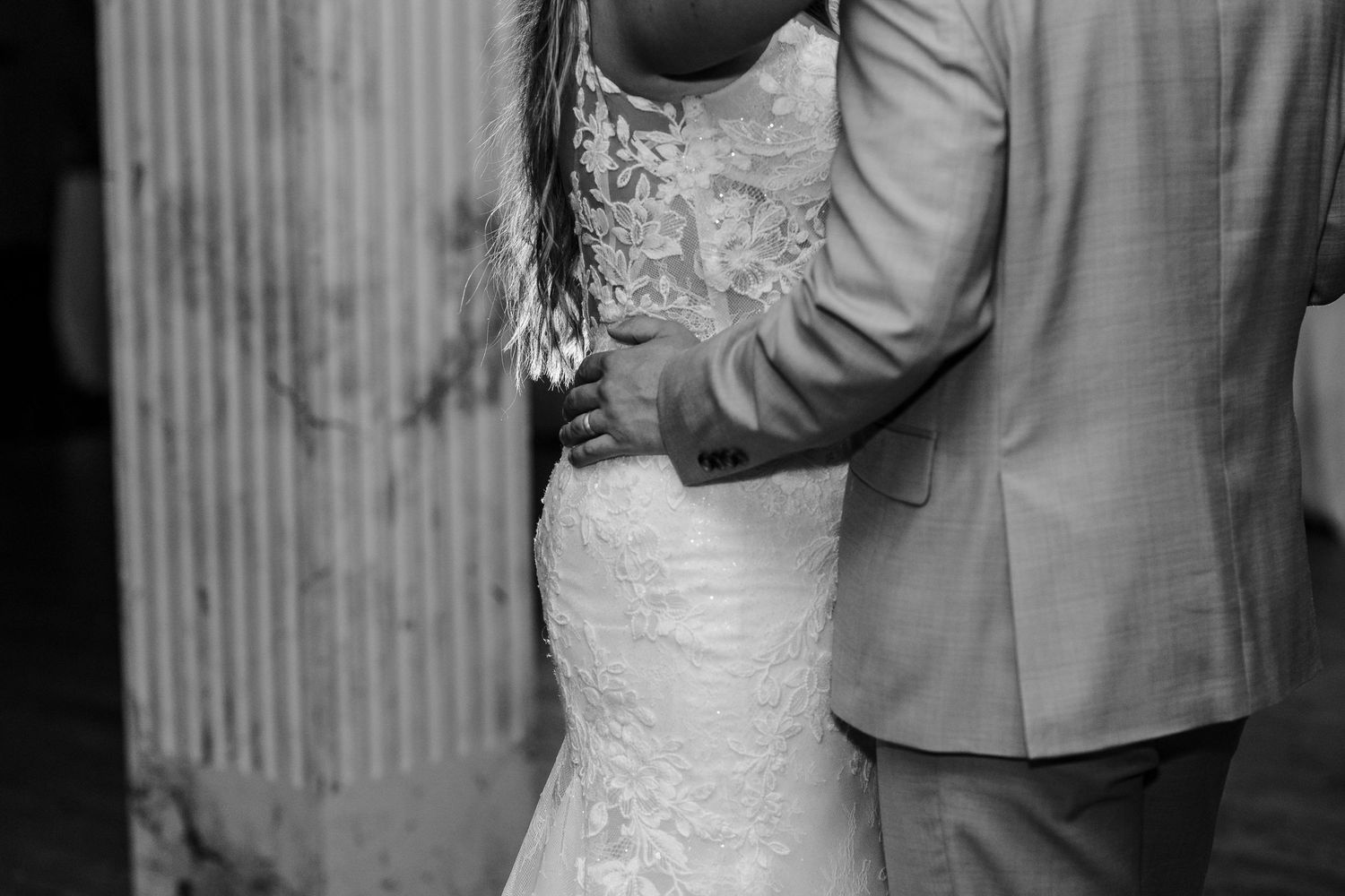 Closeup of couple in wedding attire sharing intimate dance moves at their reception.