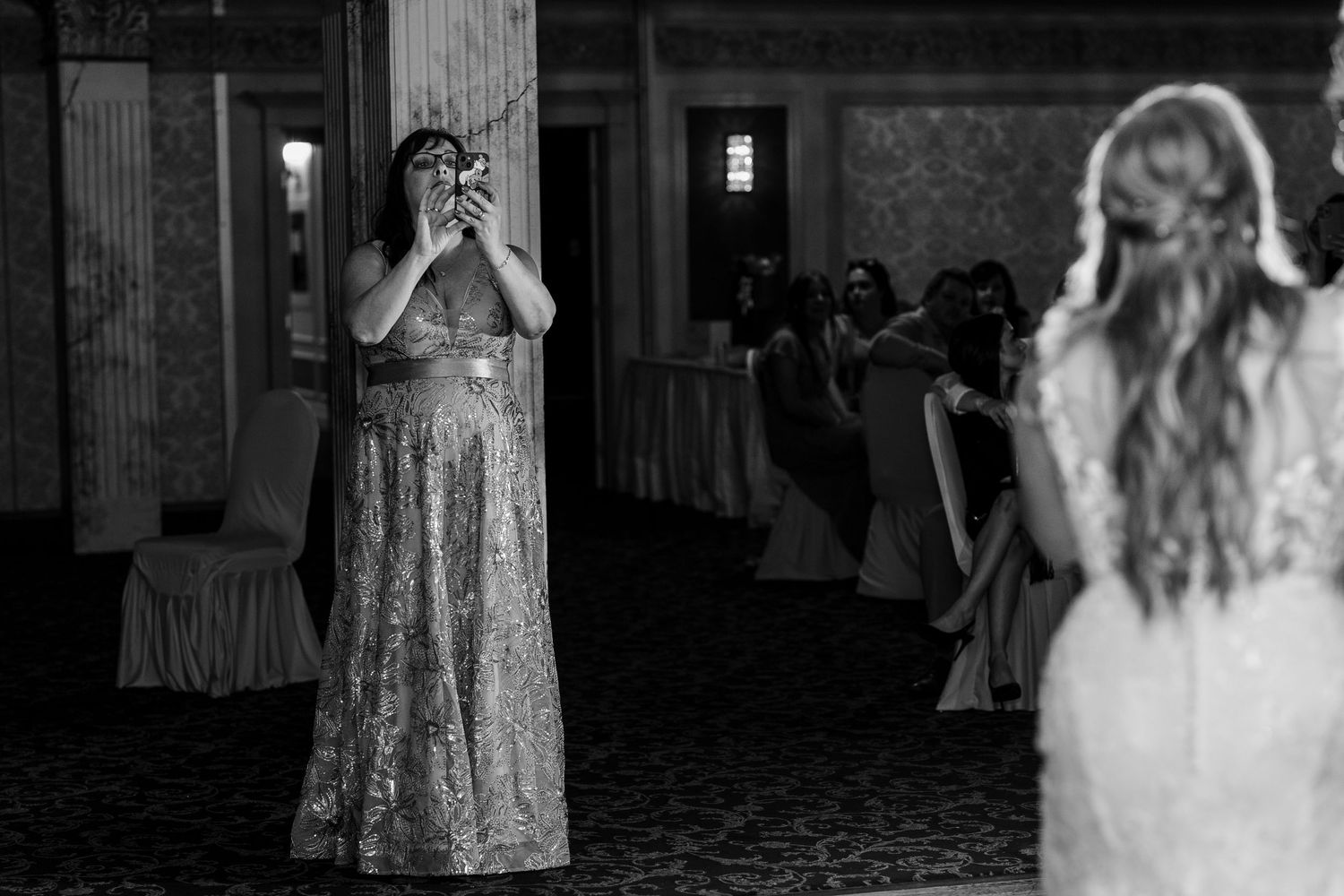 Eight black and white photos showing a wedding celebration with bridal party members in formal attire inside an elegant venue.