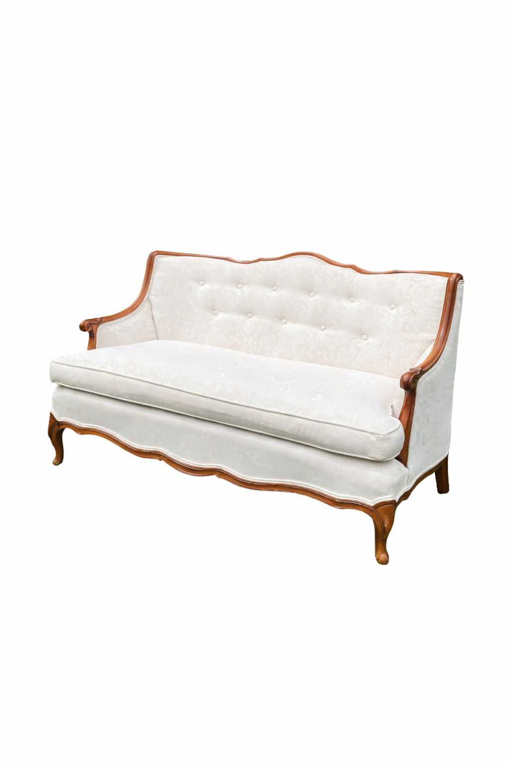 A vintage French-style settee with light gray upholstery and wooden frame sits elegantly on grass with trees in background.