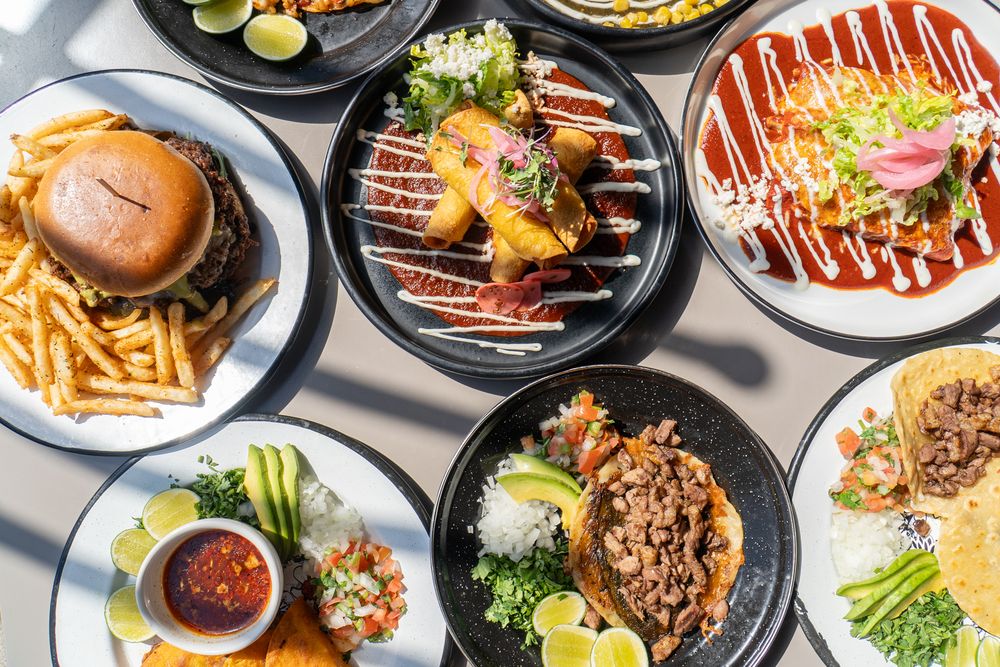 Overhead view of diverse Asian restaurant dishes including sushi, noodles, and grilled meats.