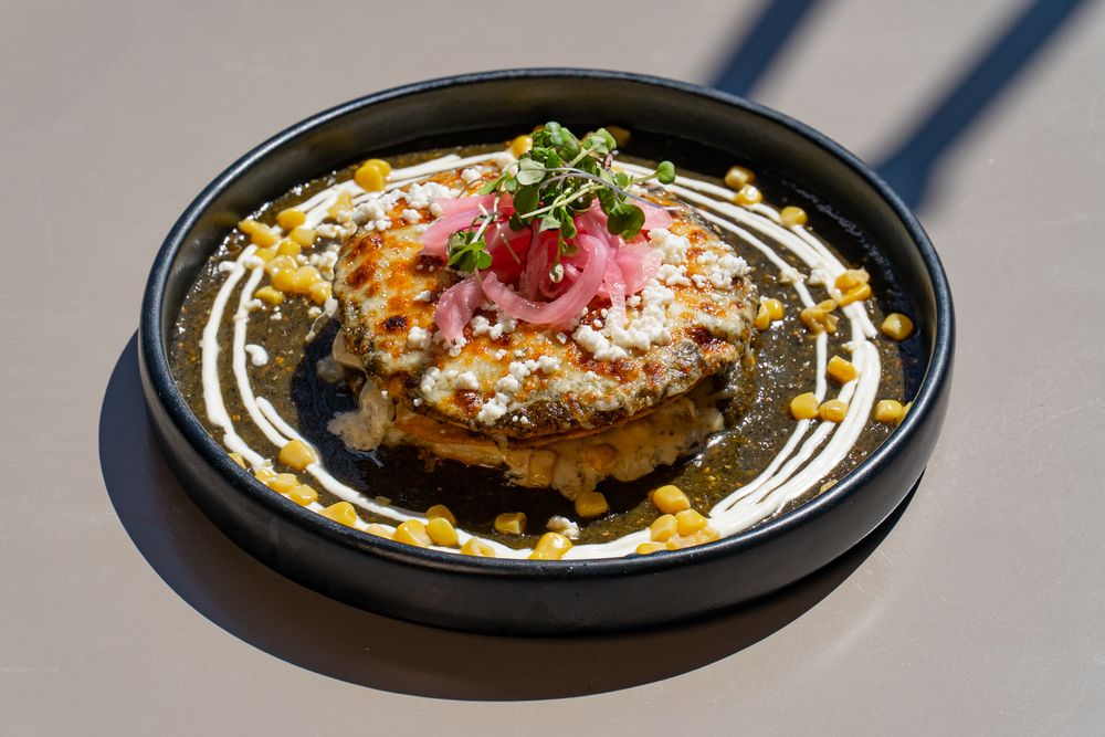 Grilled hamburger patties topped with melted cheese and sauce on black serving plates.