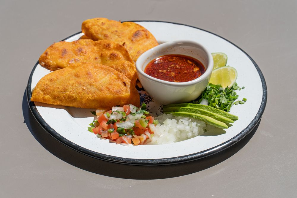 Crispy egg rolls served with dipping sauce and fresh vegetables on white plates.
