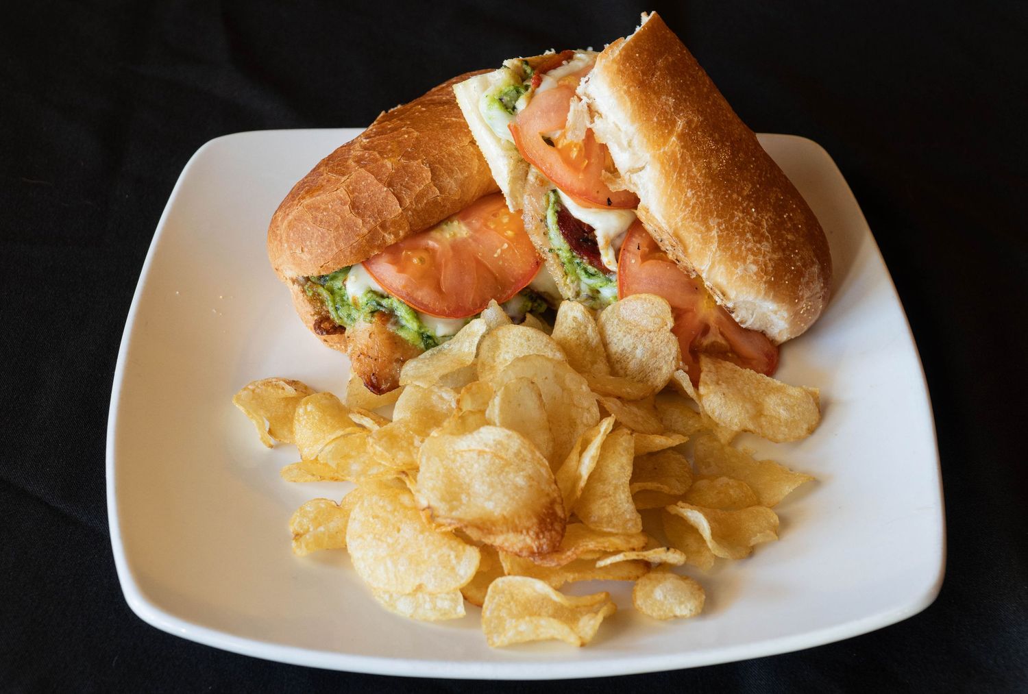Appetizer platter with potato chips and dipping sauce served on white rectangular plate.
