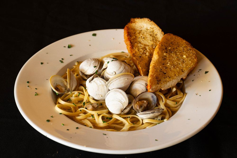 Linguine pasta with mushrooms and toasted bread in a light cream sauce served on white dinnerware.