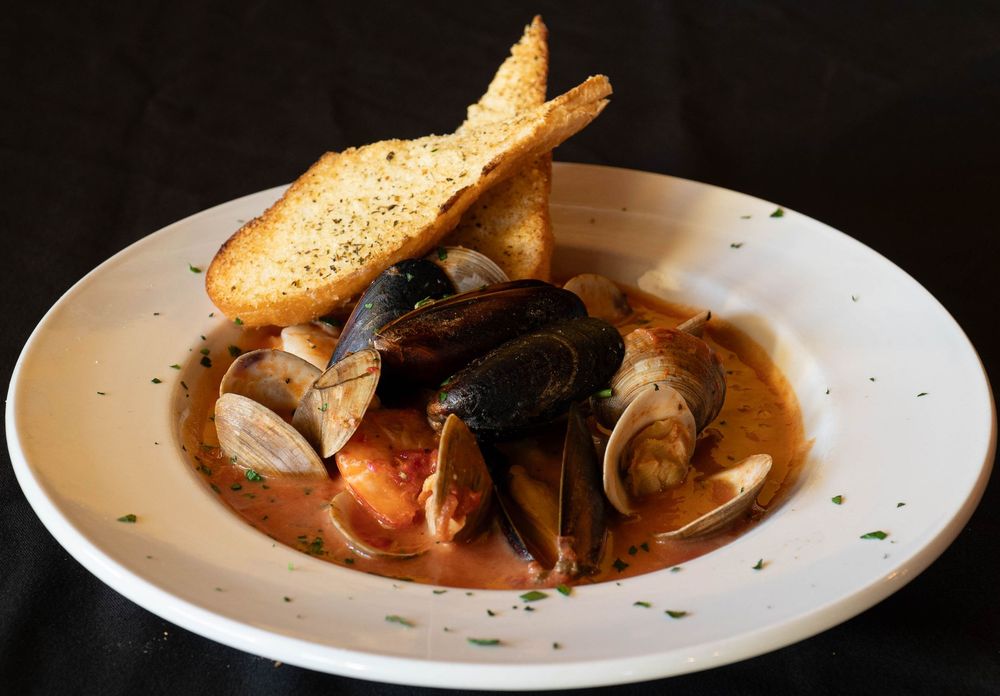Gourmet seafood dishes with toasted bread garnish served on white plates.