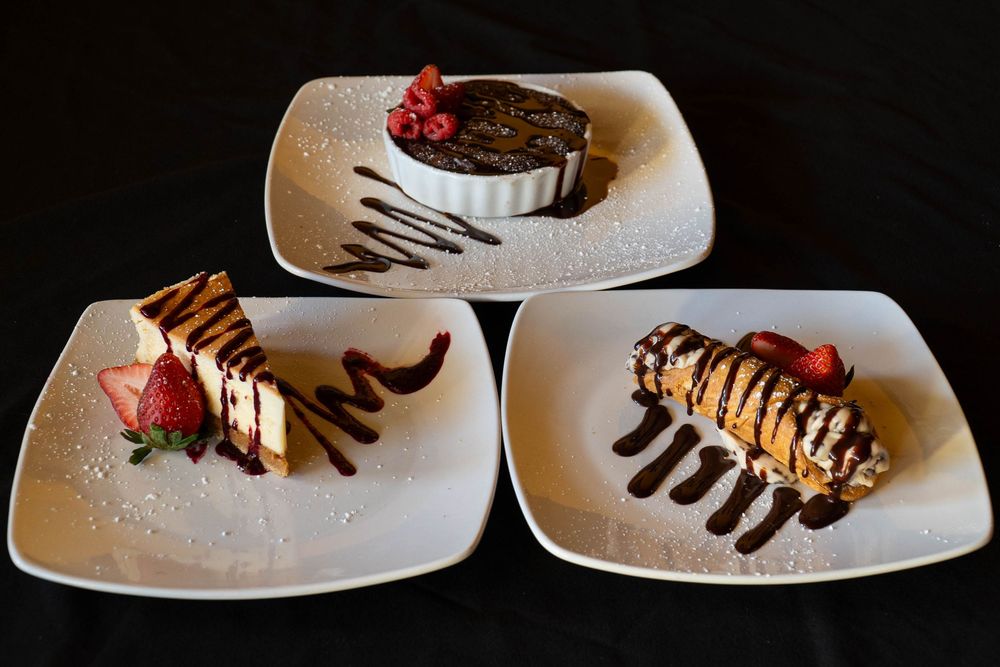 Elegant plated desserts with chocolate sauce and berries on white rectangular plates.
