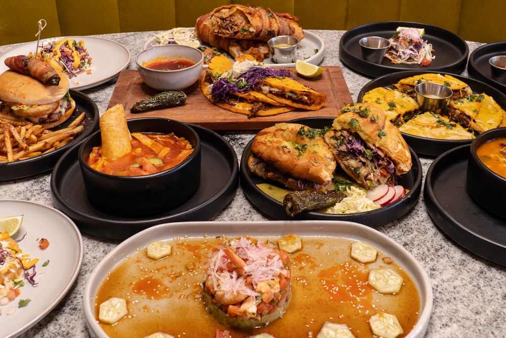 Panoramic view of various Korean dishes including soups, grilled meats, and appetizers on a dining table.