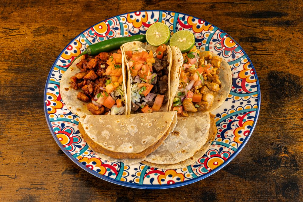 Authentic Mexican tacos served on vibrant decorative plates with traditional garnishes.